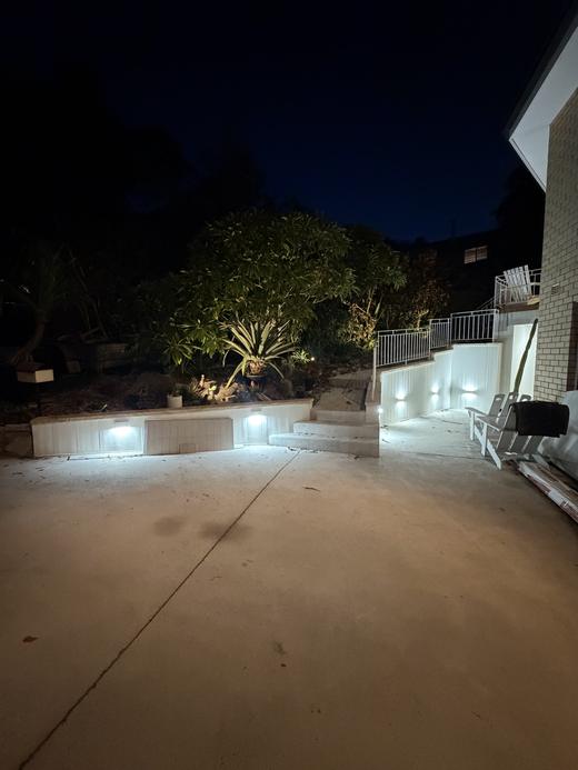 Patio and retaining wall lighting across a rear yard at night