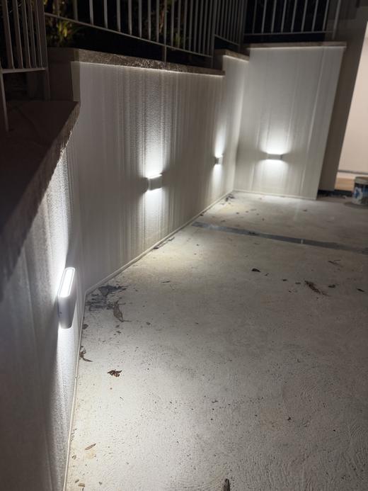 Exterior wall lighting along a rendered garden wall at night